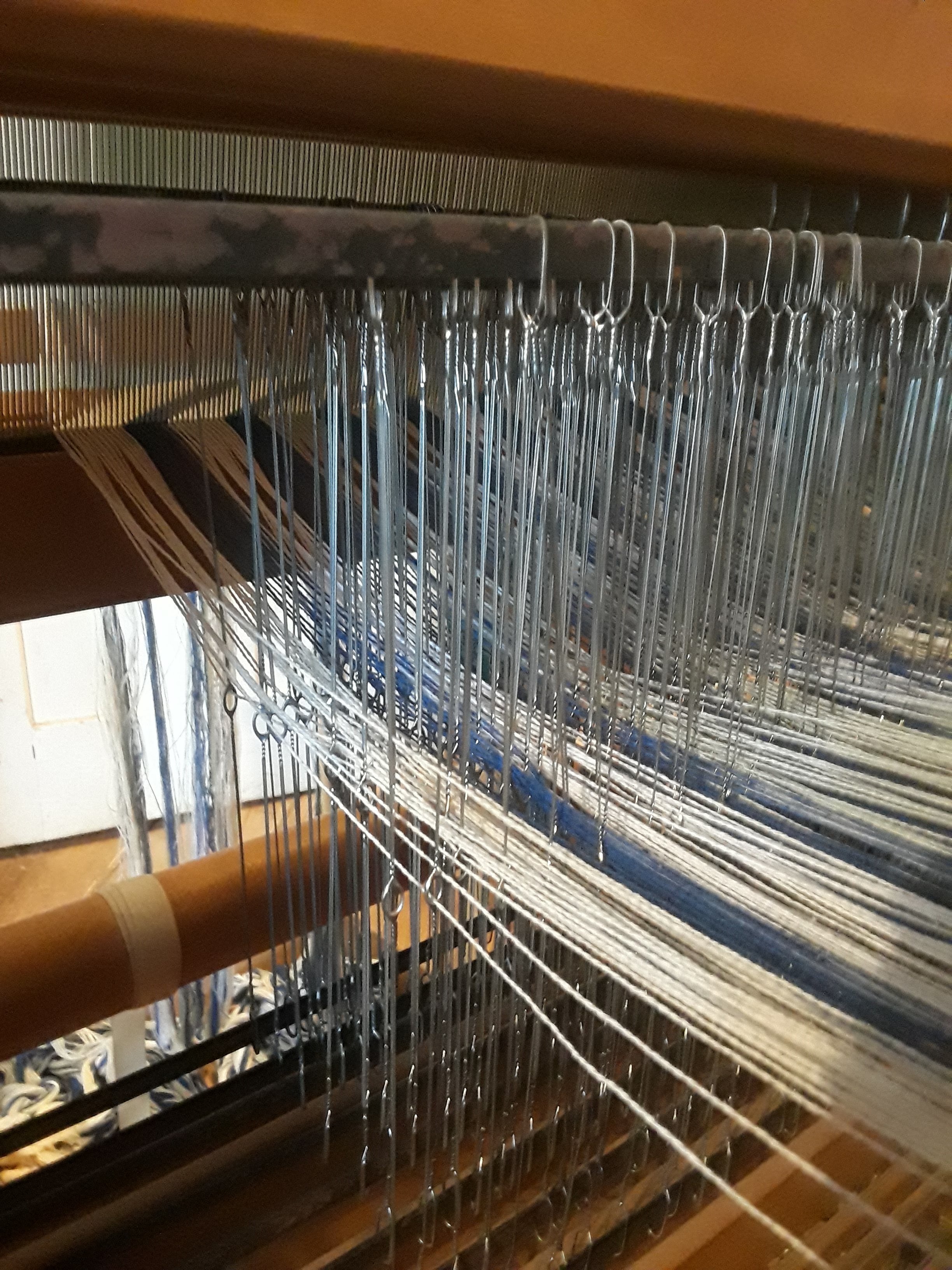 Thread going through reed and heedles.